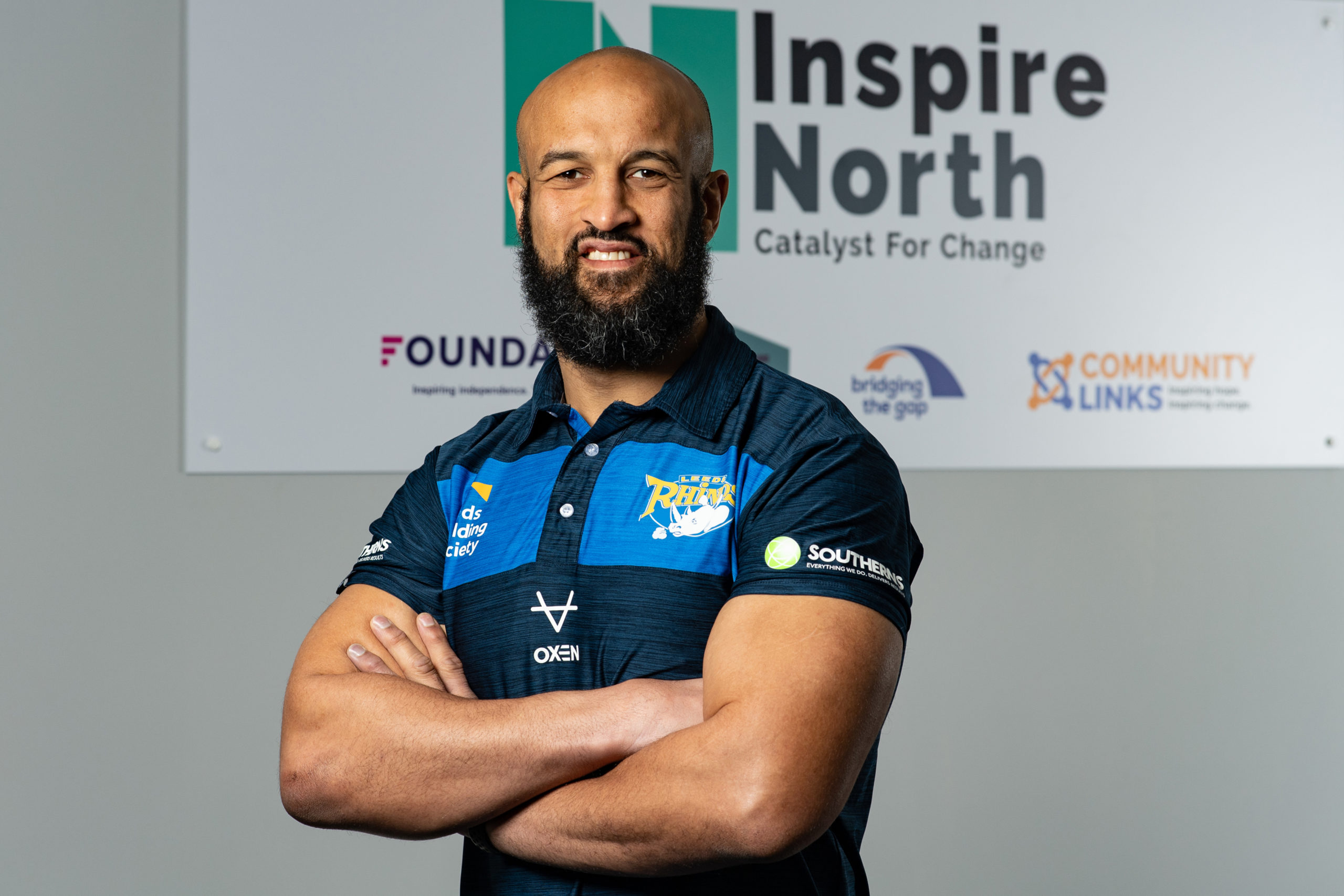 Jamie Jones-Buchanan smiling in front of Inspire North logo